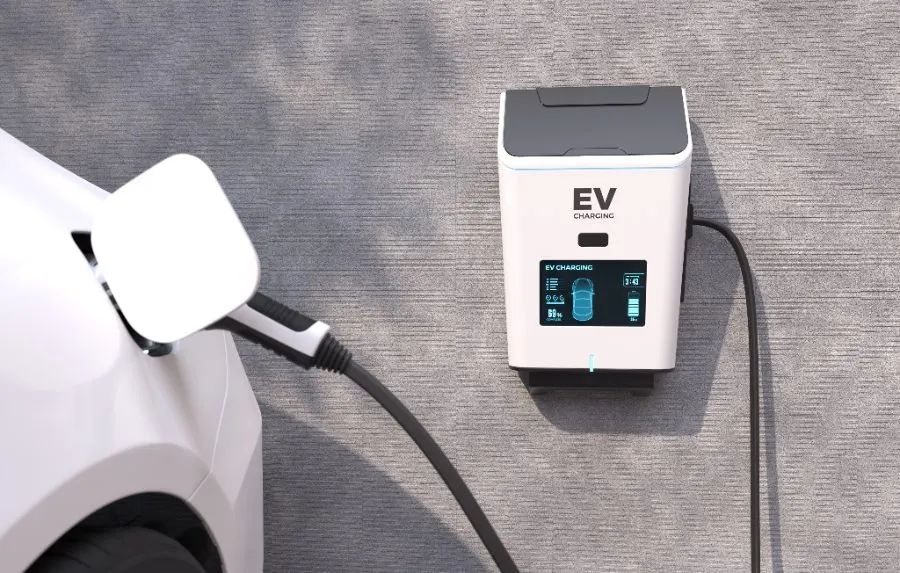 A white electric car plugged into a wall-mounted EV charging unit