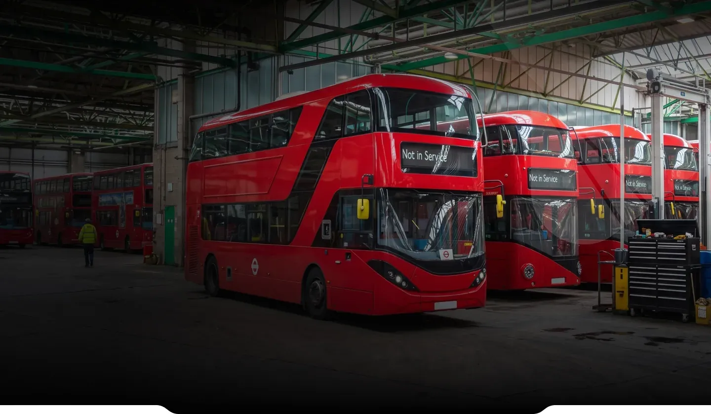 Red double-decker electric buses parked in a maintenance depot