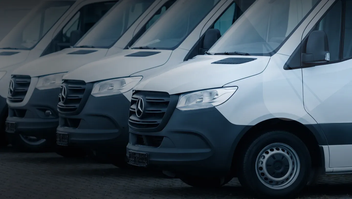 A line of white electric delivery vans parked side by side