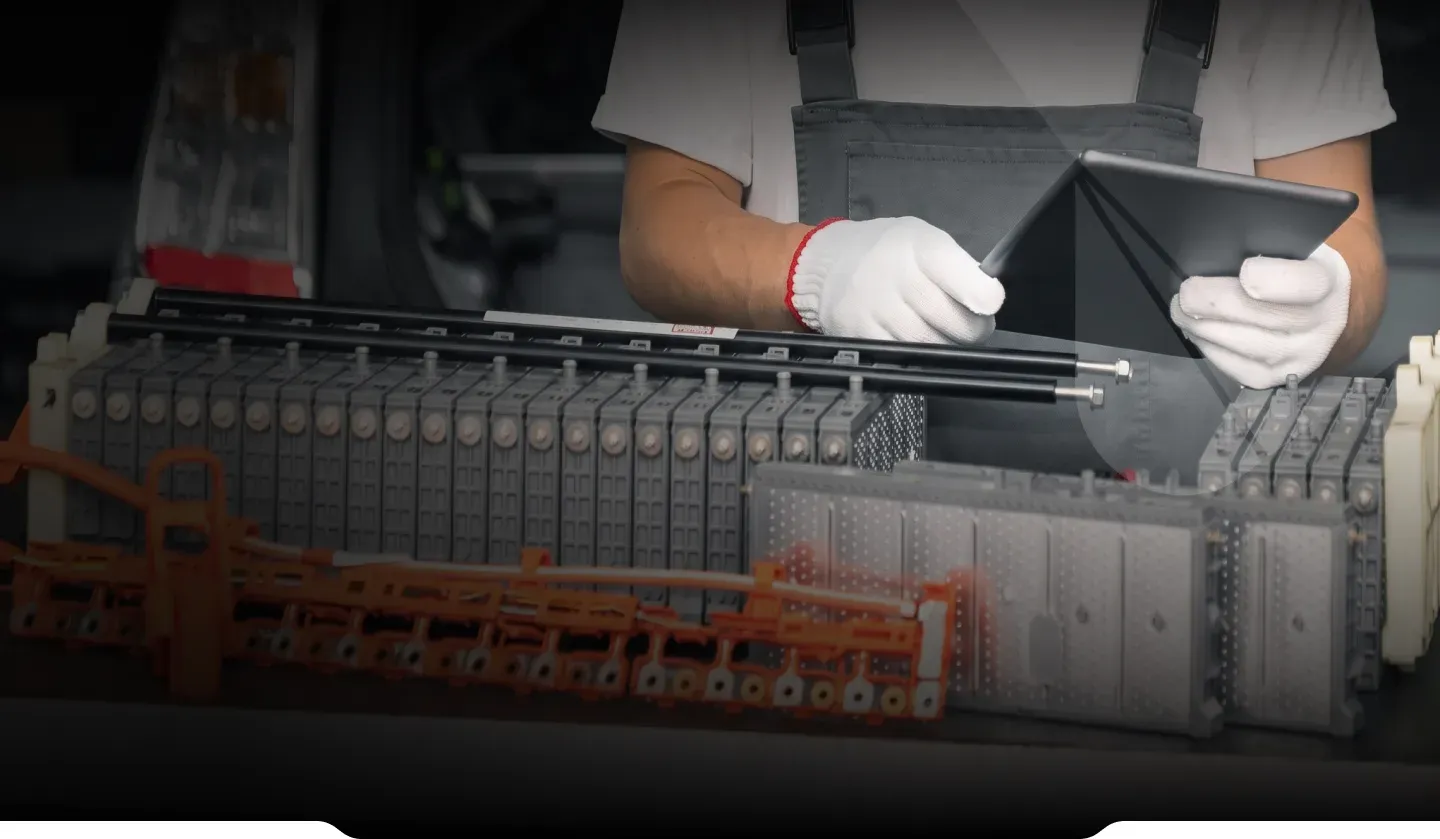 A technician in white gloves recording data on a tablet above an opened battery pack