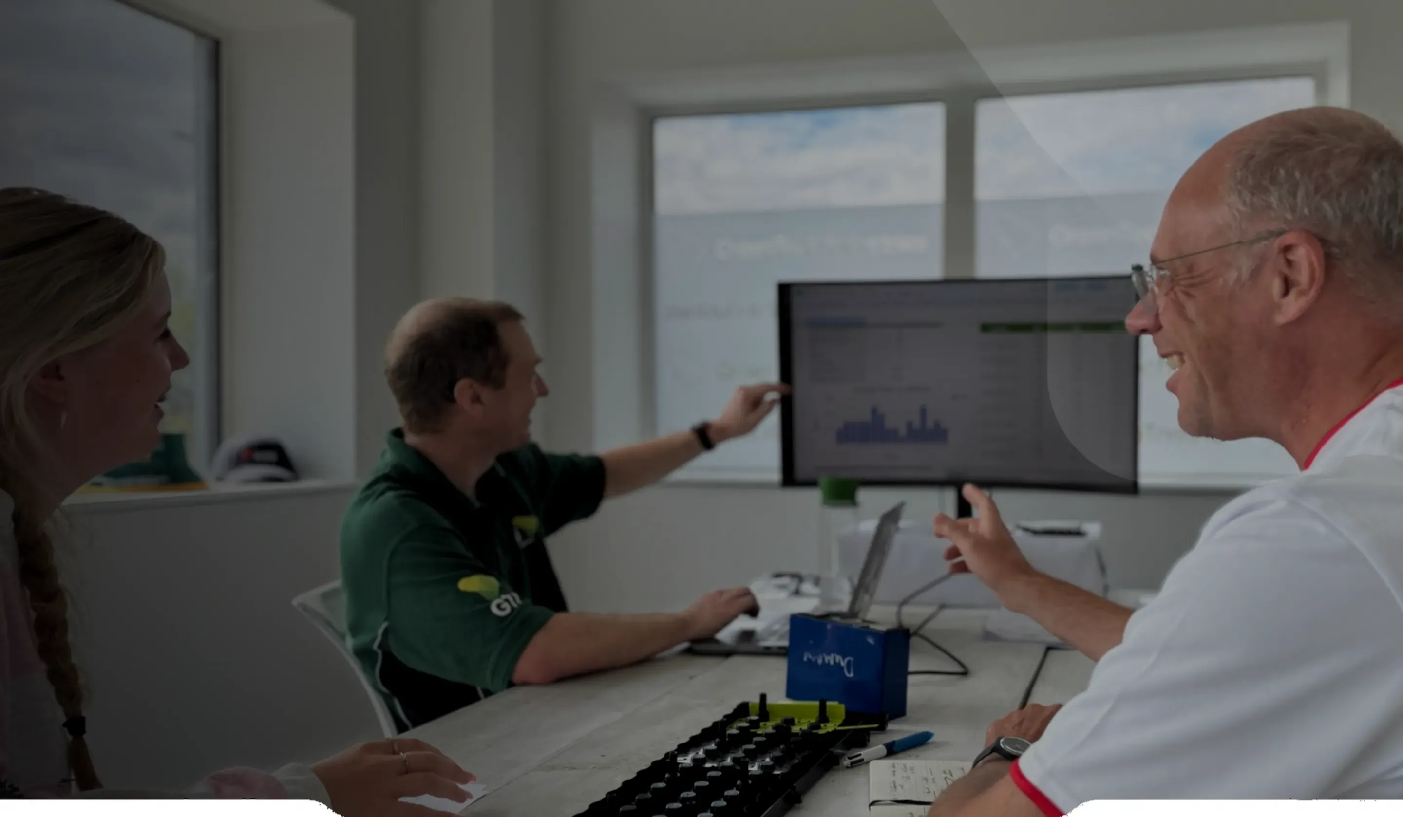 Three members of the GTI team reviewing test data on a screen in the office