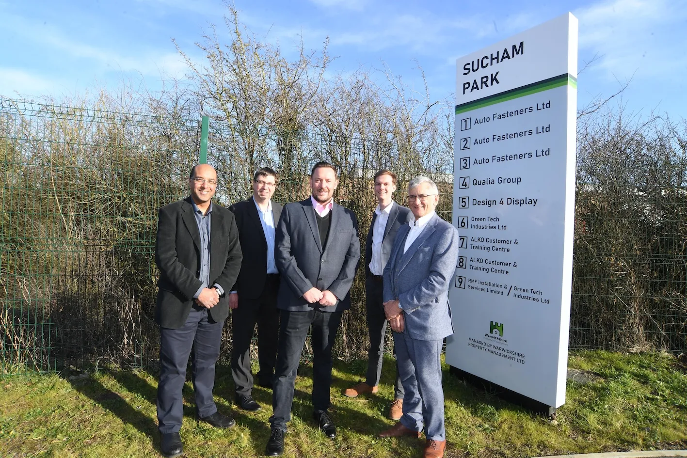 Five people in front of the Sucham Park entrance sign